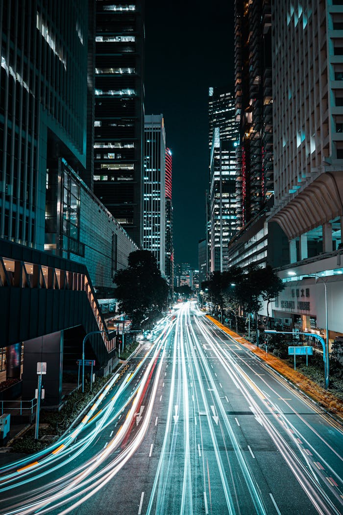 Long exposure captures light trails on a bustling Singapore city street at night.